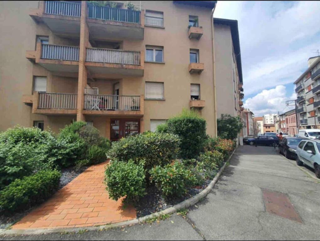 un immeuble d'appartements avec un parking en face de celui-ci dans l'établissement T2 Toulouse proche Zenith, à Toulouse
