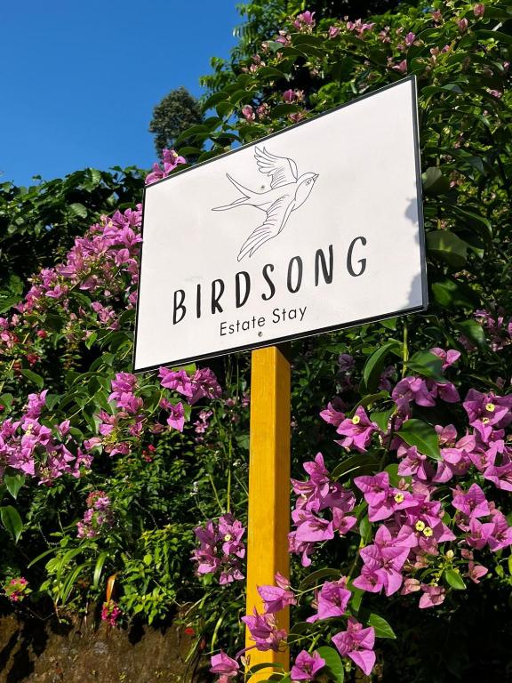 a sign for a birdong electricstay in front of flowers at Birdsong Coffee Estate Stay in Madikeri