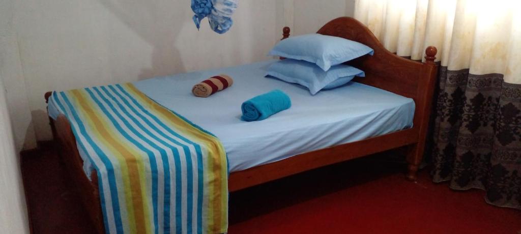 韦利格默Sriya Family Villa Weligama的一张带条纹毯子和枕头的小床