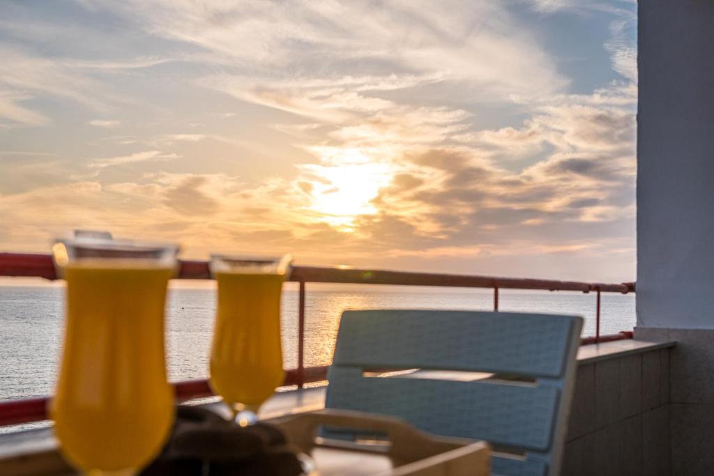 two glasses of beer on a balcony with a view of the ocean at Aria Apartment in Durrës