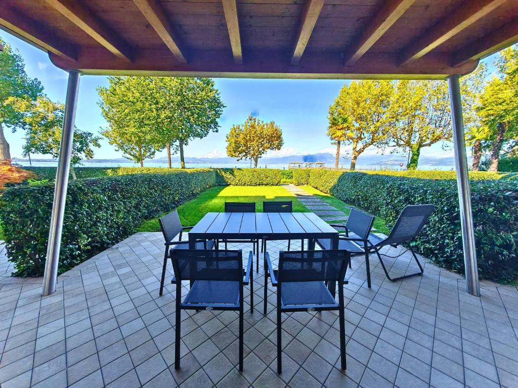 a patio with a table and chairs under a roof at SG Family - Maison Cecile in Ronchi