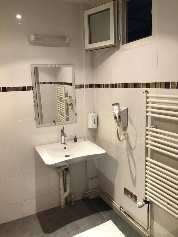 a white bathroom with a sink and a mirror at Hôtel de Ménilmontant in Paris