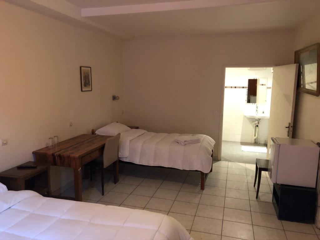 a bedroom with two beds and a desk and a table at Hôtel de Ménilmontant in Paris