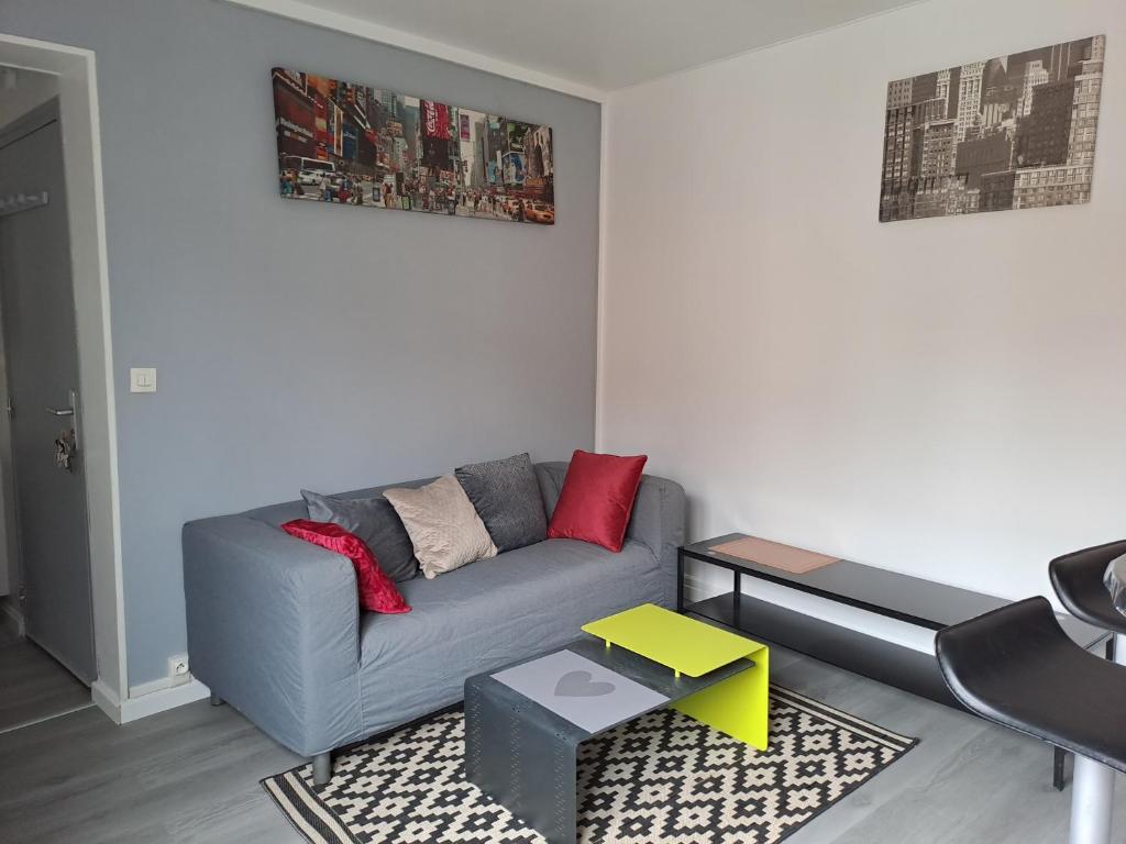 un salon avec un canapé gris et une table dans l'établissement F3 meublé proche gare, à Amiens