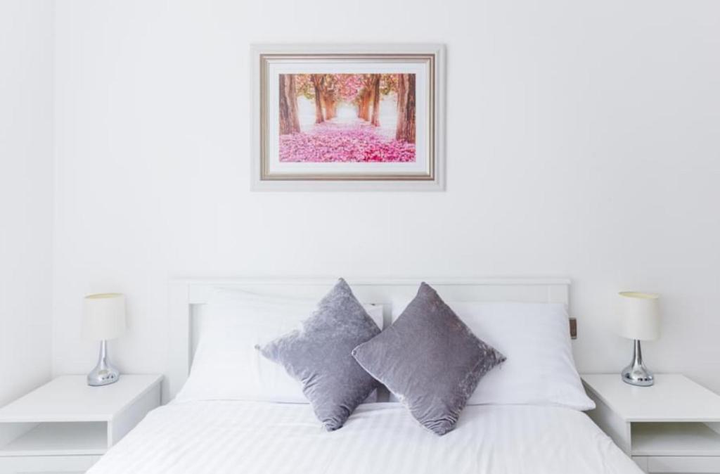 a bedroom with a white bed with a picture on the wall at Luxury Hampstead Mews House, Close to City Centre in London