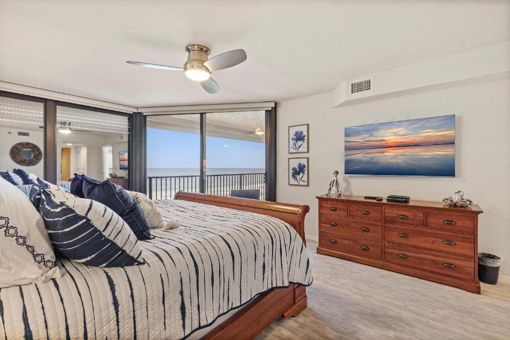 a bedroom with a bed and a dresser with a window at Chadham by the Sea 413 in New Smyrna Beach