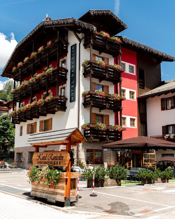 a large building with flower boxes and a sign in front of it at Romantic Charming Hotel Rancolin in Moena