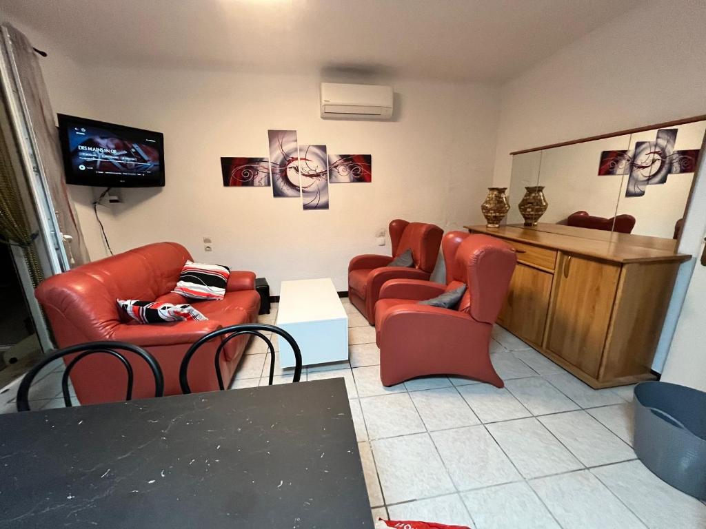- un salon avec des chaises rouges et une télévision dans l'établissement Appartement rez-de-jardin proche du centre ville et de la cure, à Amélie-les-Bains-Palalda
