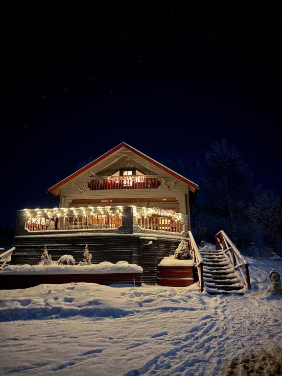 a building covered in lights in the snow at night at Frosty Brook Cottage Hosted by Hygge Host in Lehtola