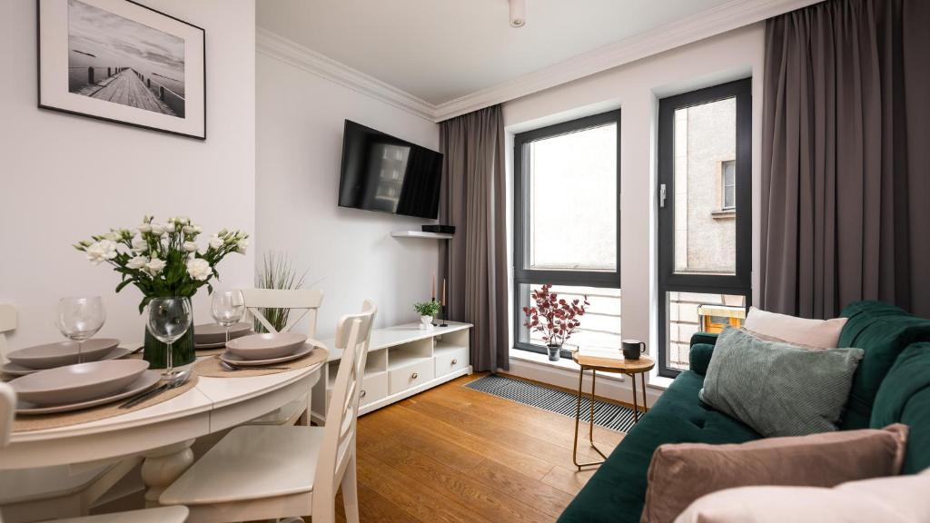 a living room with a table and a green couch at Flatbook - City Center Apartment Bank Polsk in Gdynia