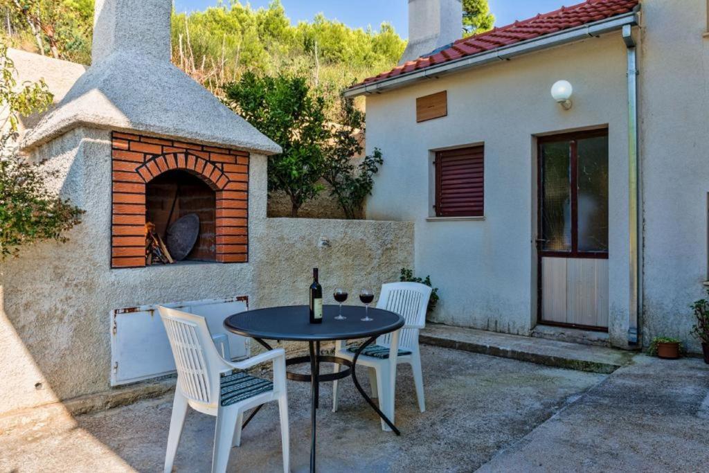 eine Terrasse mit einem Tisch und Stühlen sowie einem Pizzaofen in der Unterkunft Apartment Tafra 2 in Lokva Rogoznica