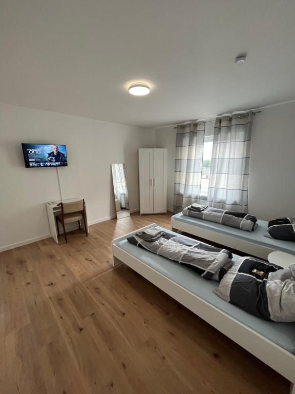 a room with three beds and a tv on the wall at Übernachtung by Tag in Kassel