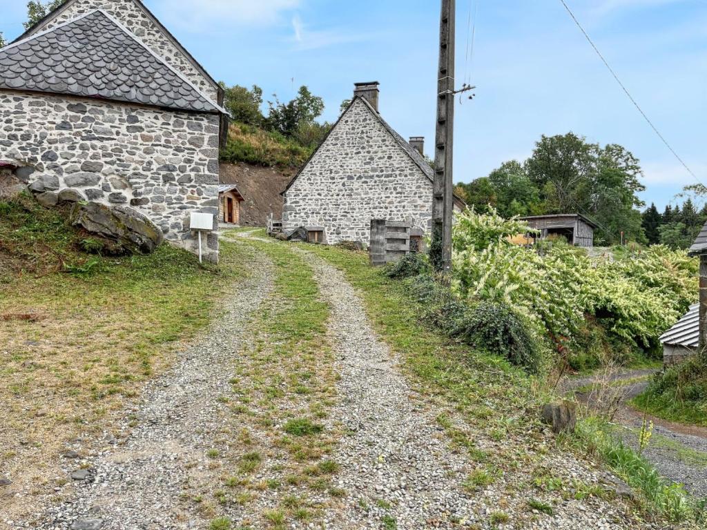 droga gruntowa prowadząca do dwóch kamiennych budynków w obiekcie Maison de campagne spacieuse à Chastreix avec cheminée w mieście Chastreix