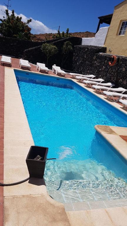 a blue swimming pool with lounge chairs and a black bucket at Club JM Lanzarote in Tabayesco