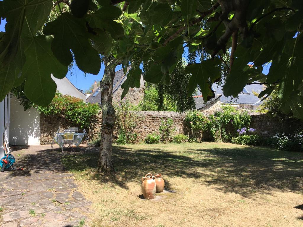un groupe de pots assis sous un arbre dans une cour dans l'établissement Agréable maison de vacances, à Quimiac
