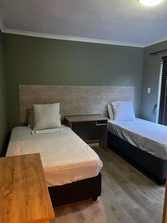 a room with two beds and a wooden table at VB Accomodation (STATION HOME) in Cape Town