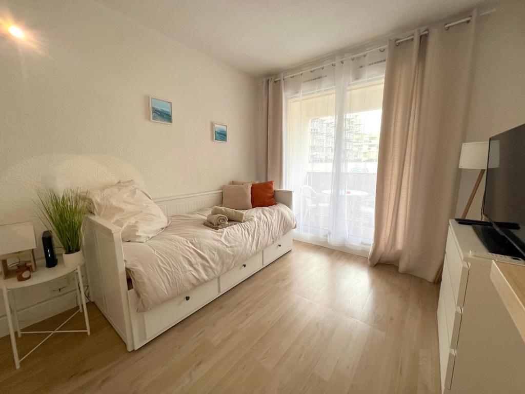 une chambre blanche avec un lit et une fenêtre dans l'établissement Studio Ocean Crest avec clim et wifi, à La Grande Motte