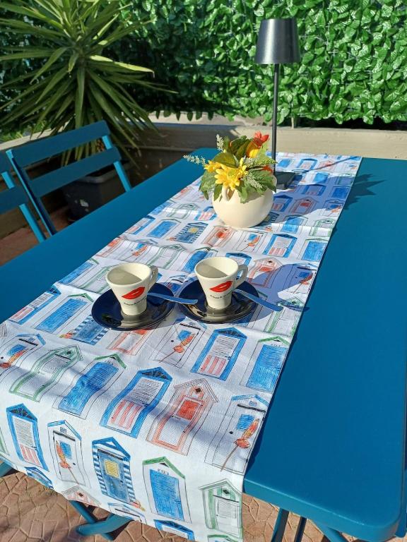 a blue table with two cups and a flower on it at Stella Maris - Private Apartment in Bari