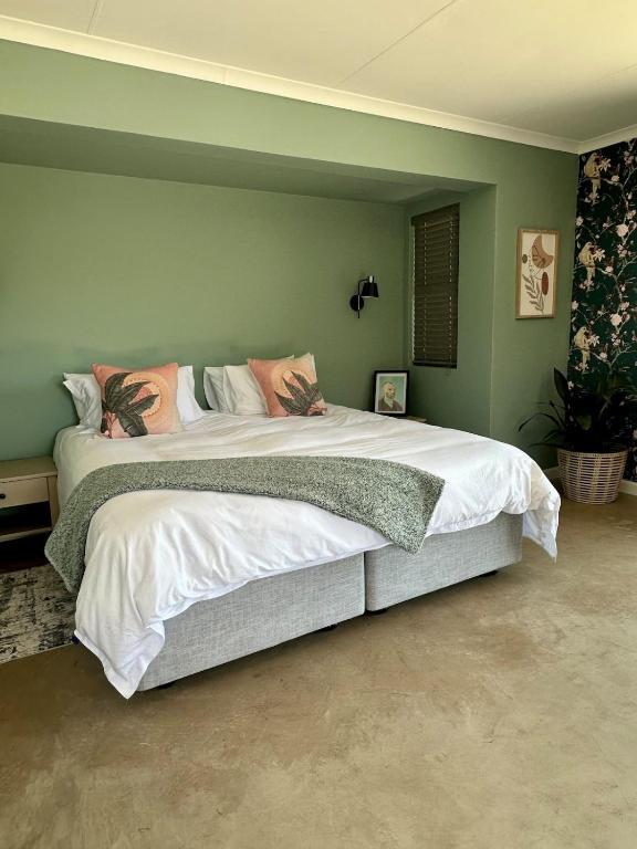 a large bed in a bedroom with green walls at Stylish Cottage on secure estate in Howick