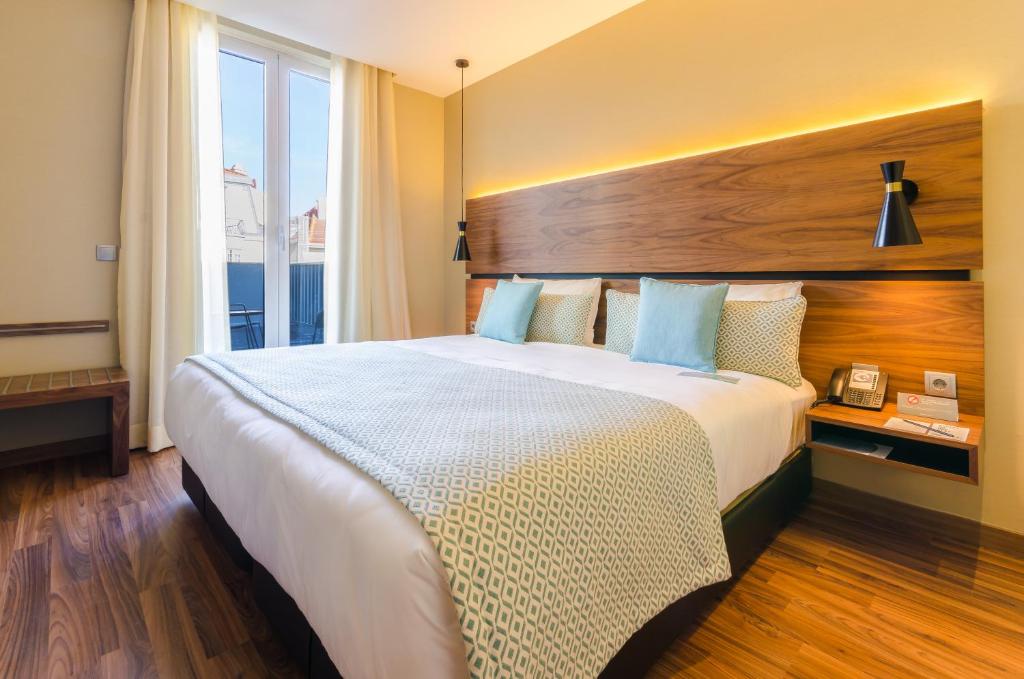 A bedroom with a bright balcony doorway and a view toward Lisbon rooftops.