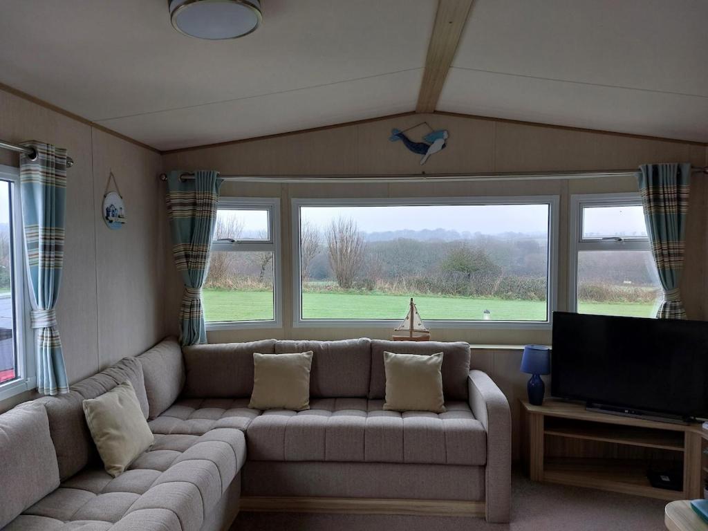 Una sala de estar con un sofá y un televisor de pantalla plana. en Gateway to Cornwall, en St Austell