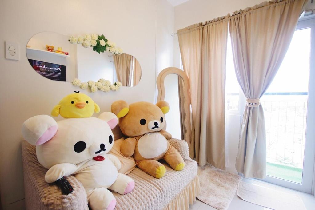 three stuffed teddy bears sitting on a chair in a room at SMDC VINE Residence Rilakkuma-theme 2BR w Balcony in Manila