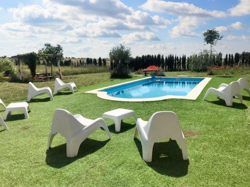 a group of white chairs and a swimming pool at Comfortable House with Shared Pool in Alcaracejos in Alcaracejos