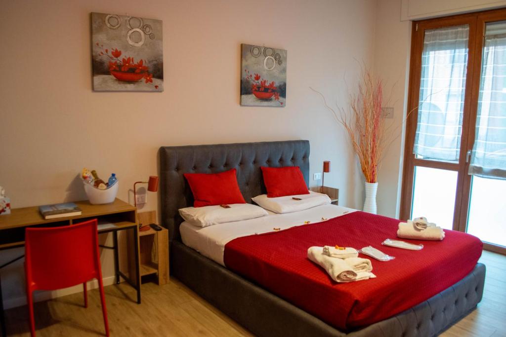 sypialnia z łóżkiem z czerwonymi poduszkami i biurkiem w obiekcie Emmanueli65 fronte clinica per 4 matrimoniale e castello w mieście Piacenza