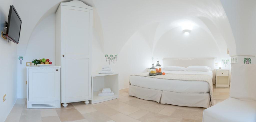 a white bedroom with a bed and a mirror at Dimora Dell'Osanna in Carovigno