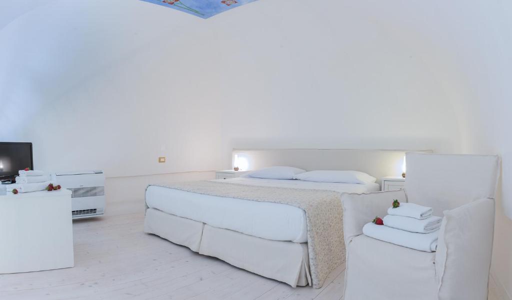 a white bedroom with a bed and a chair at Dimora Dell'Osanna in Carovigno