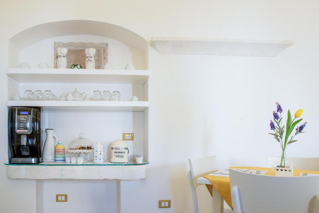 a kitchen with a table with a coffee maker and a shelf at Dimora Dell'Osanna in Carovigno