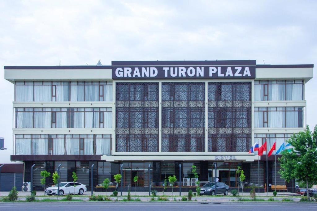 a grand trump plaza building with cars parked in front at Grand Turon Plaza Hotel in Tashkent