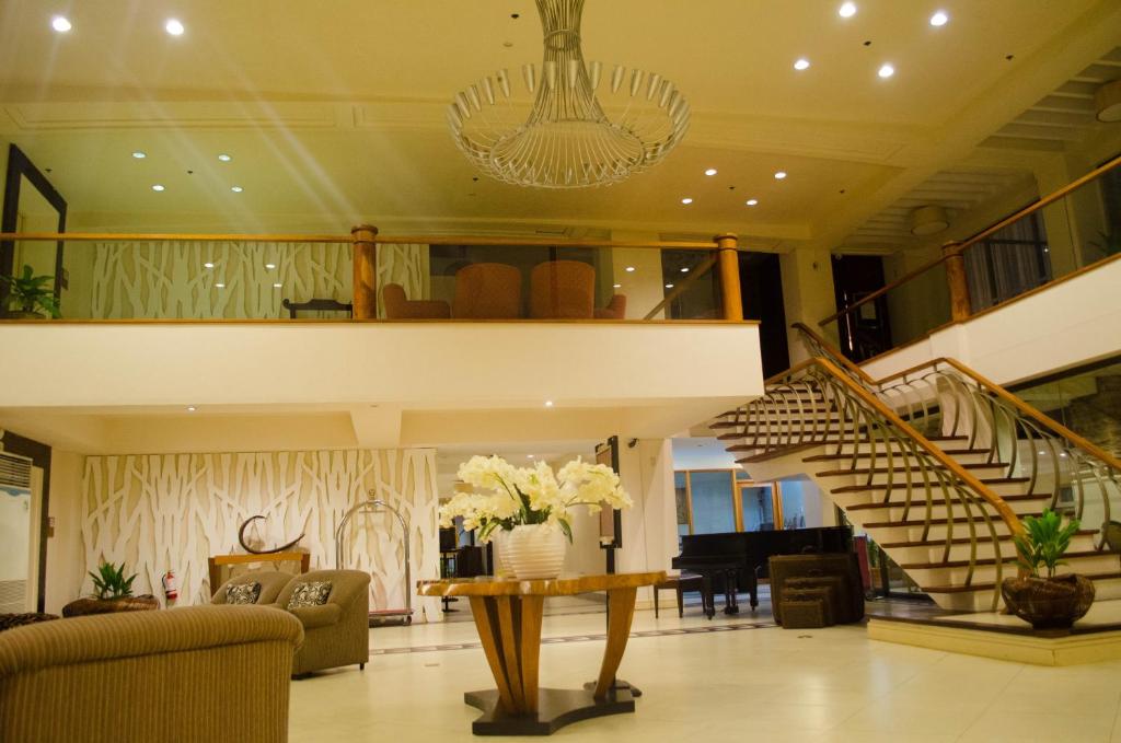 a lobby with a staircase and a living room at Hotel Tavern Surigao in Surigao