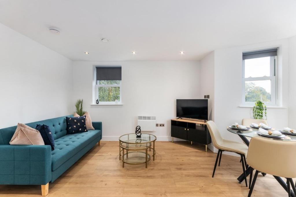 ein Wohnzimmer mit einem blauen Sofa und einem Tisch in der Unterkunft Modern 2-Bedroom Apartment, Leatherhead, Sleeps 4 in Leatherhead