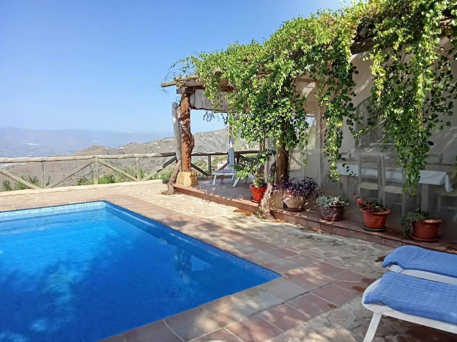 a swimming pool with a pergola next to a house at Casa Rural en Málaga, donde el tiempo se detiene in Las Casillas