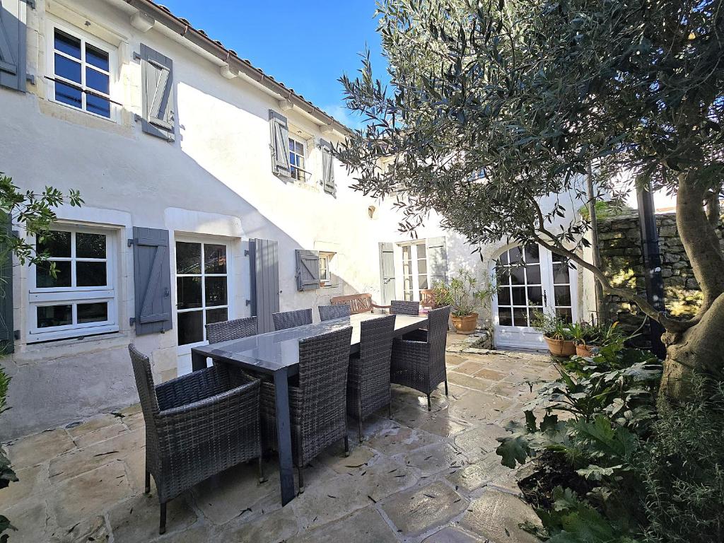 une table et des chaises devant un bâtiment dans l'établissement Sous le passage, à La Flotte