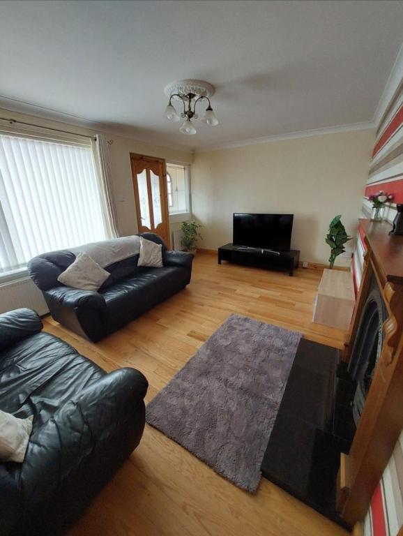 Una sala de estar con un sofá y un televisor. en Welcoming 4 bedroom townhouse with free parking on premises, en Lisnaskea