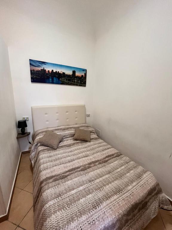 a bed in a white room with a picture on the wall at House del Corso Calatafimi in Palermo