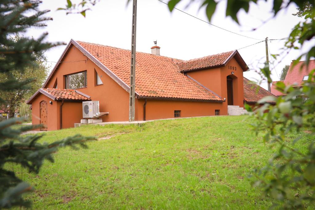 a house on a grassy hill in front of a house at Lawki Booking in Ławki