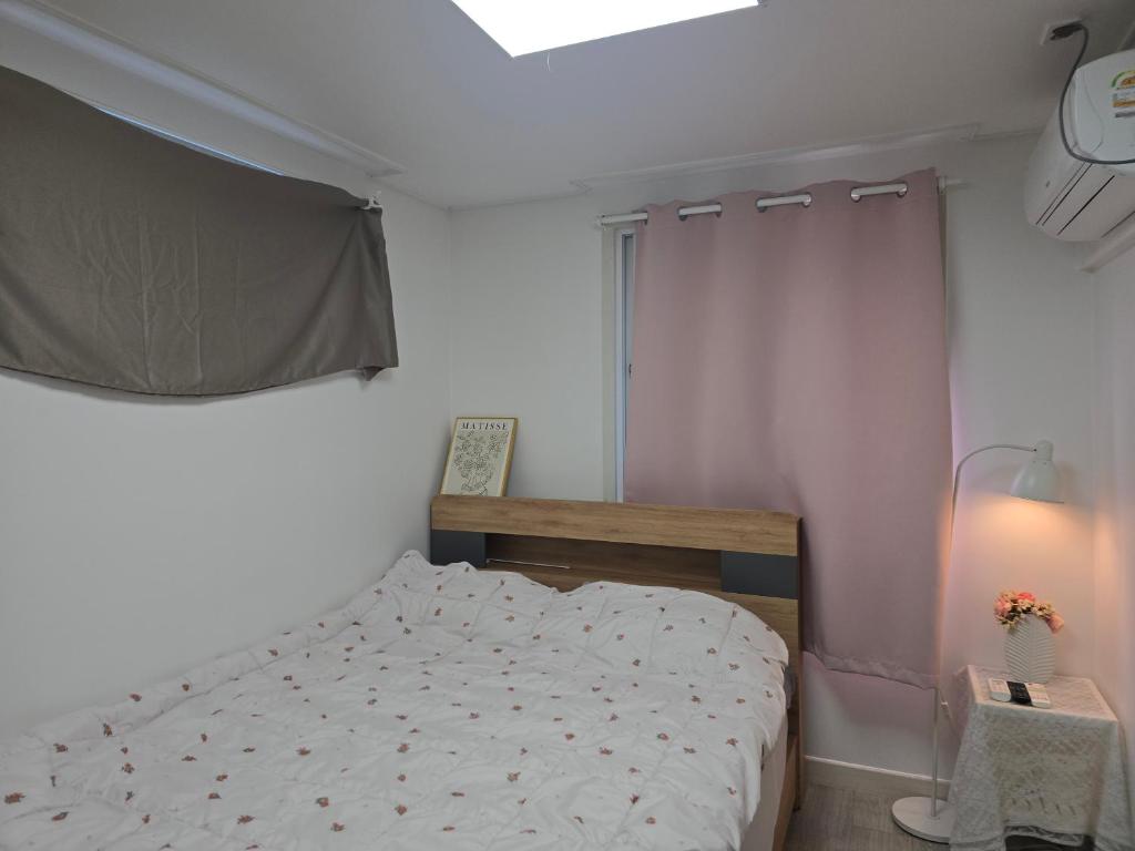a small bedroom with a bed and a window at Oneul house in Daegu