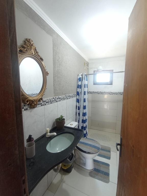 a bathroom with a sink and a toilet and a mirror at Casa na Beira da Praia de Capão da Canoa in Capão da Canoa