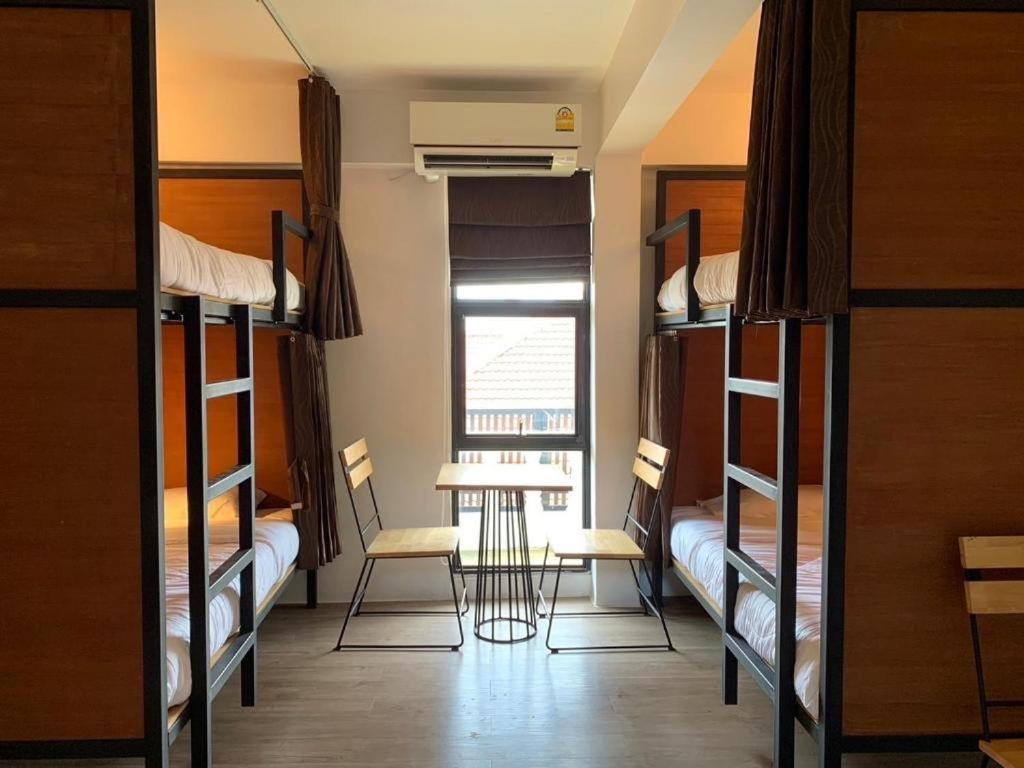 a room with bunk beds and a table and chairs at Lazy Gibbon 2 Chiang Mai - Haiya in Chiang Mai