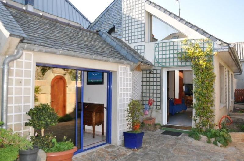 une maison blanche avec une grande porte coulissante en verre dans l'établissement Maison à 100m de la mer avec WIFI, place Ste-Anne à TREGASTEL - Réf 43, à Trégastel