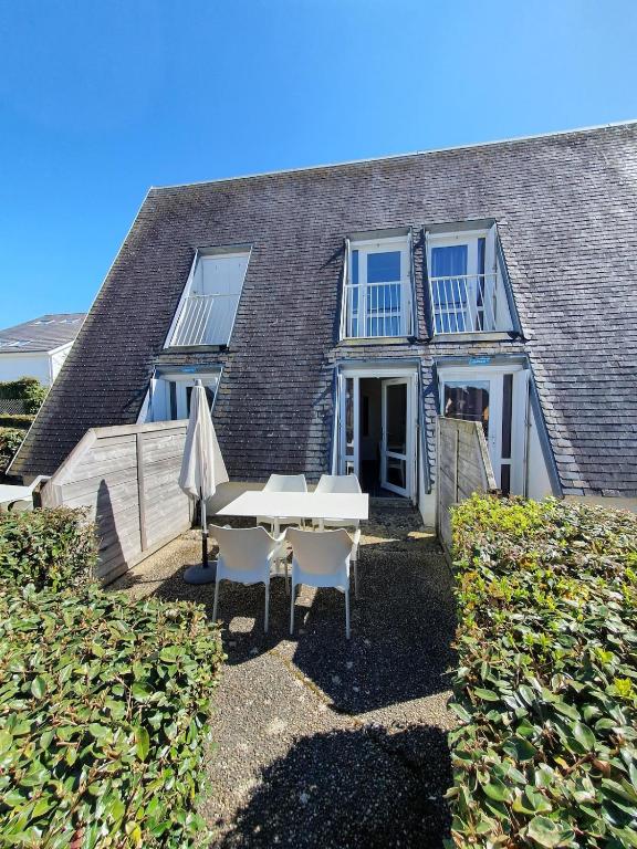 une table et un parasol devant une maison dans l'établissement Duplex proche de la mer avec piscine, à Guidel