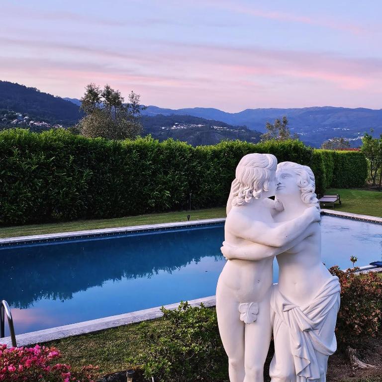 a statue of two people standing next to a pool at Solar Alegria Lodge in Oliveira de Frades