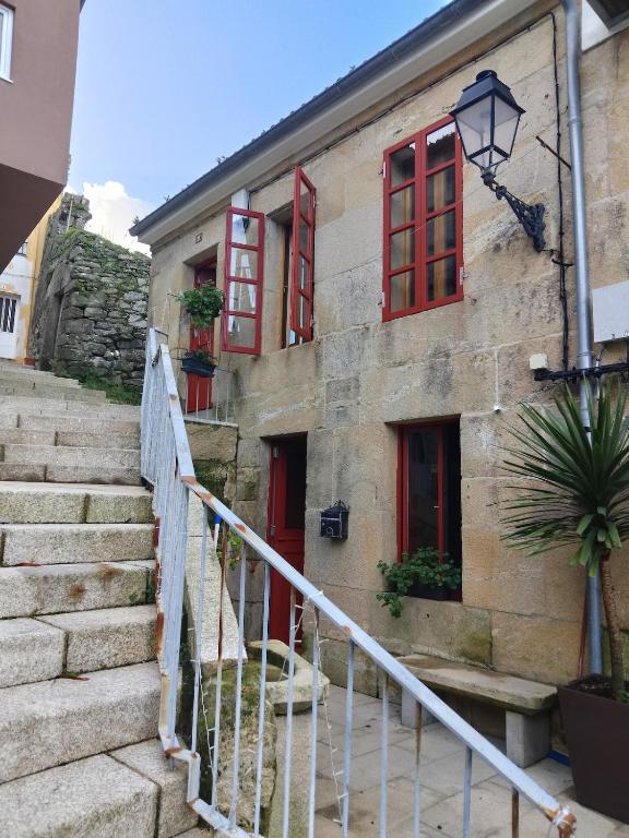 an old building with red windows and stairs at Loft O Viñal in Muros