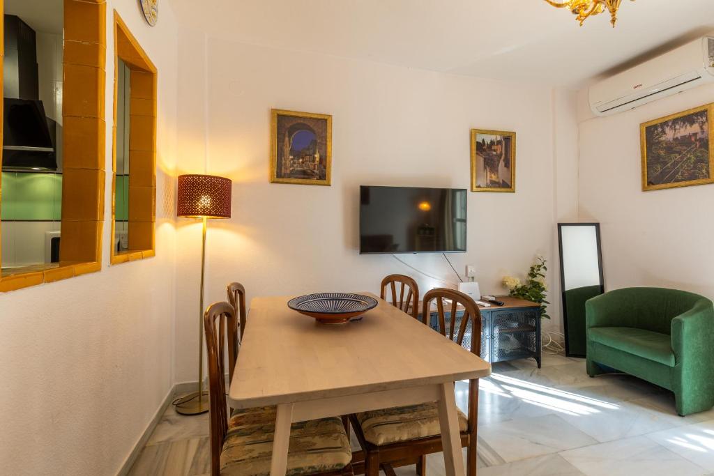 comedor con mesa, sillas y TV en Apartamentos Ruta de la Sierra, en Cenes de la Vega