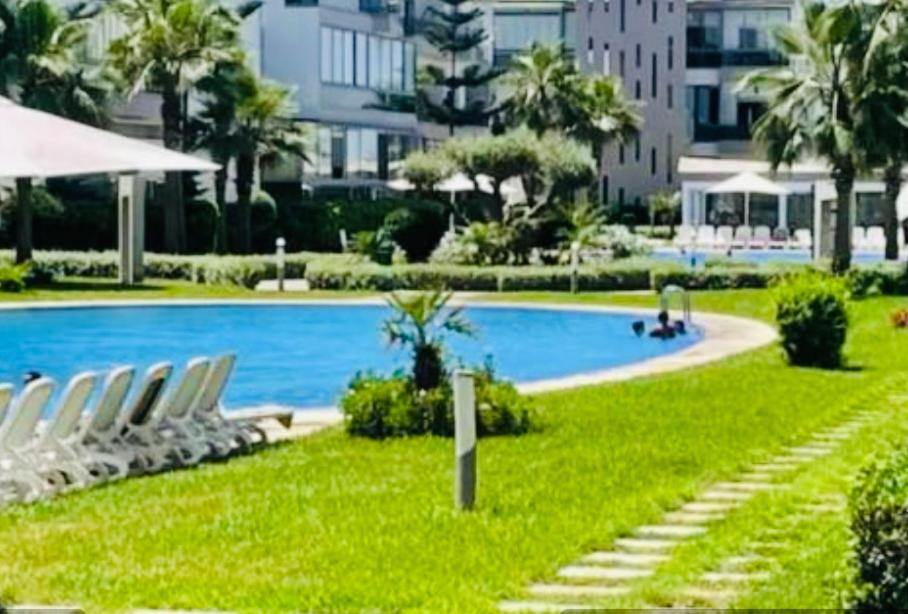 a swimming pool with two lounge chairs in the grass at Blanca beach in Sidi Rahal