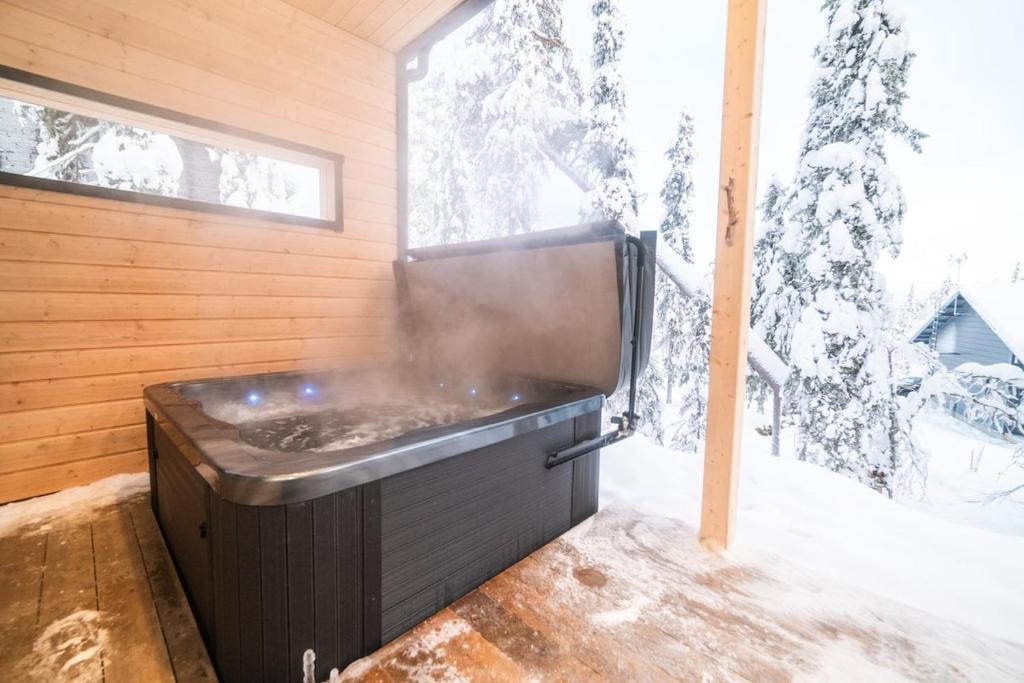 a hot tub in a room with a snow covered tree at Villa Havu A in Syöte