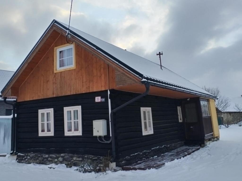 una casa negra con nieve en el suelo en Drevenica Viki 1, en Pribylina